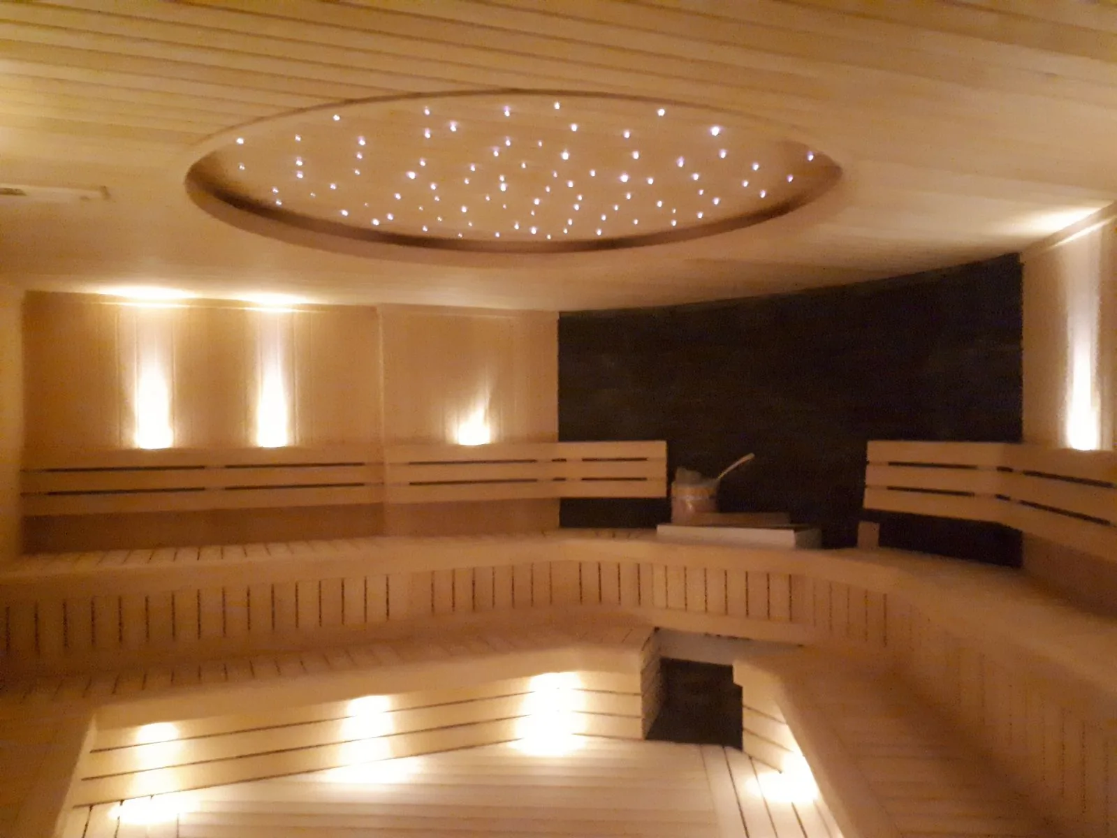 Yıldız tavan aydınlatmalı geniş ahşap sauna oturma alanı